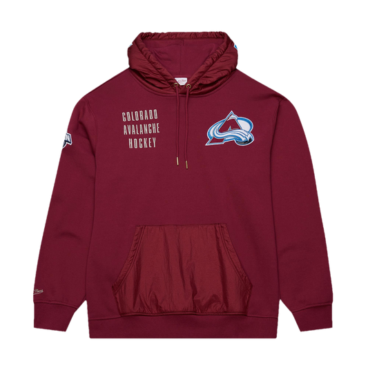 Burgundy hoody with windbreaker material on the pocket area and hood. Both the logos of Mitchell and Ness and the NHL Western Conference are embroidered on the right sleeve. On the left breast, a fully-colored Avalanche primary logo is embroidered, with "Colorado Avalanche Hockey" embroidered on the other. "Avalanche" is written on the hood.