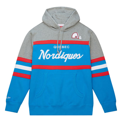 Grey, primary blue, and red Quebec Nordiques hoody. The color grey goes from the hood area down to middle of both arms. The red, white, and blue color scheme runs from the middle body area downward. The Nordiques logo is embroidered on the upper left breast. The words "Quebec Nordiques" on embroidered on the center of the hoody. The Mitchell and Ness letter logo is on the right wrist.