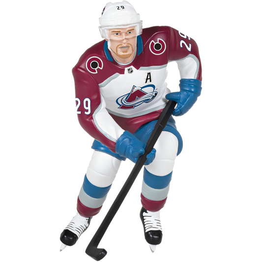 This is an ornament of Colorado Avalanche center Nathan Mackinnon. He is portrayed in the Avalanche away uniform, which is primary white. He has a white helmet, blue gloves and pants, with striped socks with Blue on top, white in the middle, and burgundy on the bottom, finishing the design out with Black colored skates. He is holding a black hockey stick, and on the back of his Jersey it has his last name "Mackinnon" with his number "29" right below it. On the front it has the avs logo, with an "A" patch.