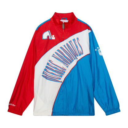 Red, white, and blue Quebec Nordiques full-zip jacket. The color red runs around the front and back neckline as well as the upper shoulders and down the entire right arm. White runs across the stomach area. Blue runs from the lower left hip, entire right arm, and whole back. The words "Quebec Nordiques" is on the middle of the jacket. The Mitchell and Ness logo script in on the lower right wrist. The old NHL logo is on the left arm. There are also two Nordiques logos- one  on the front and one on the back.