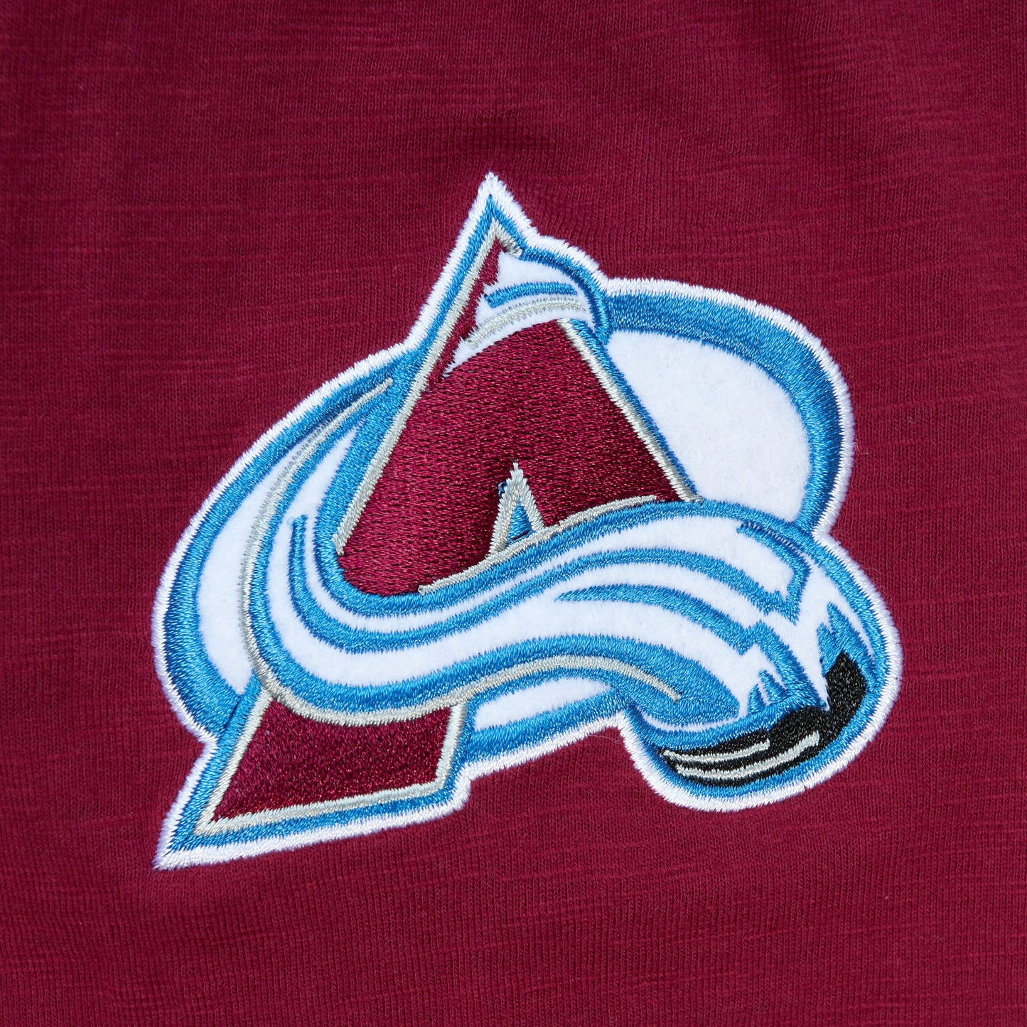 Close up of embroidered, full color, small Avalanche logo with burgundy background.